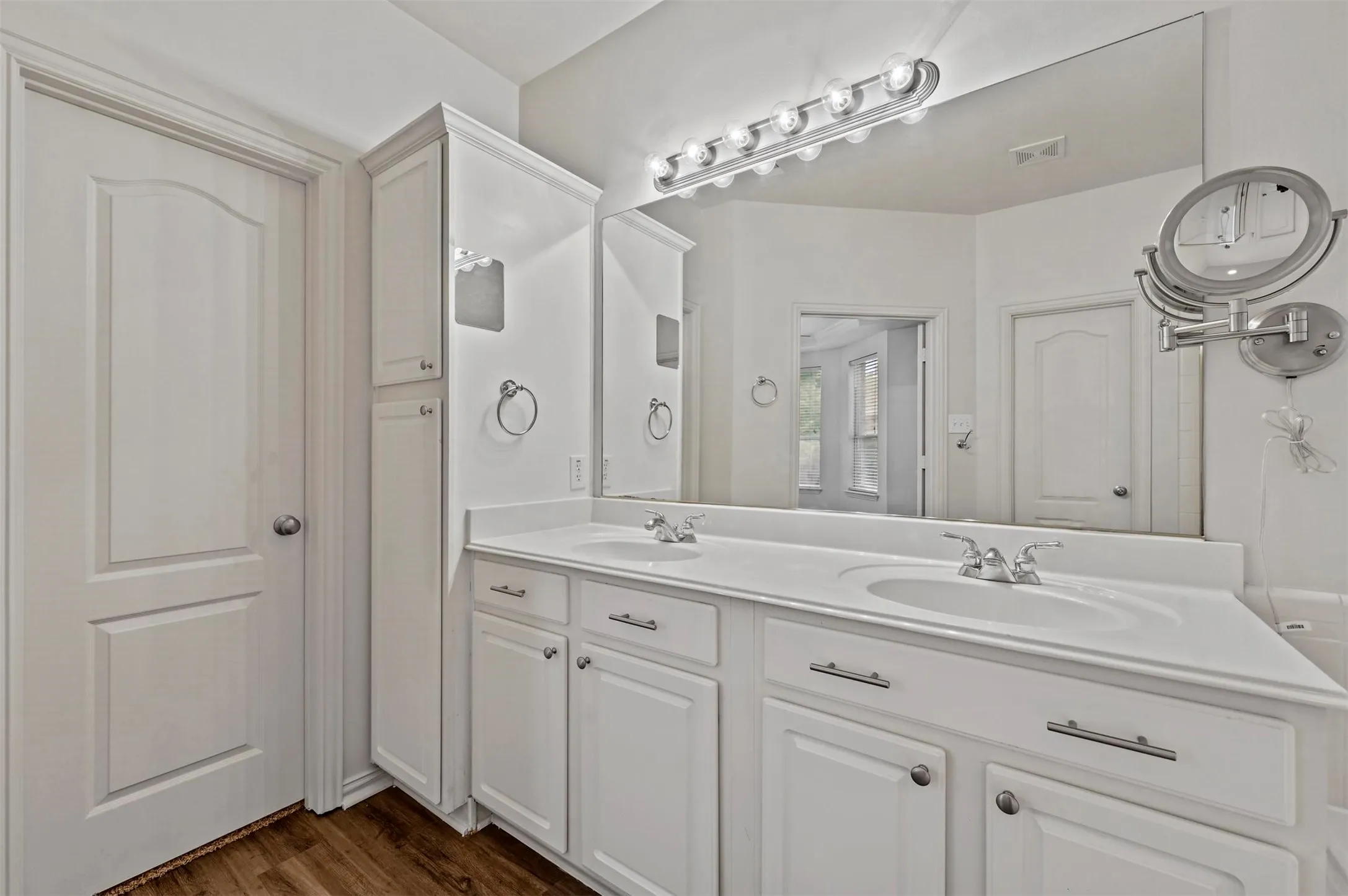 Bathroom featuring a double vanity with white cabinetry and integrated sinks, a wide mirror, and a built-in linen tower