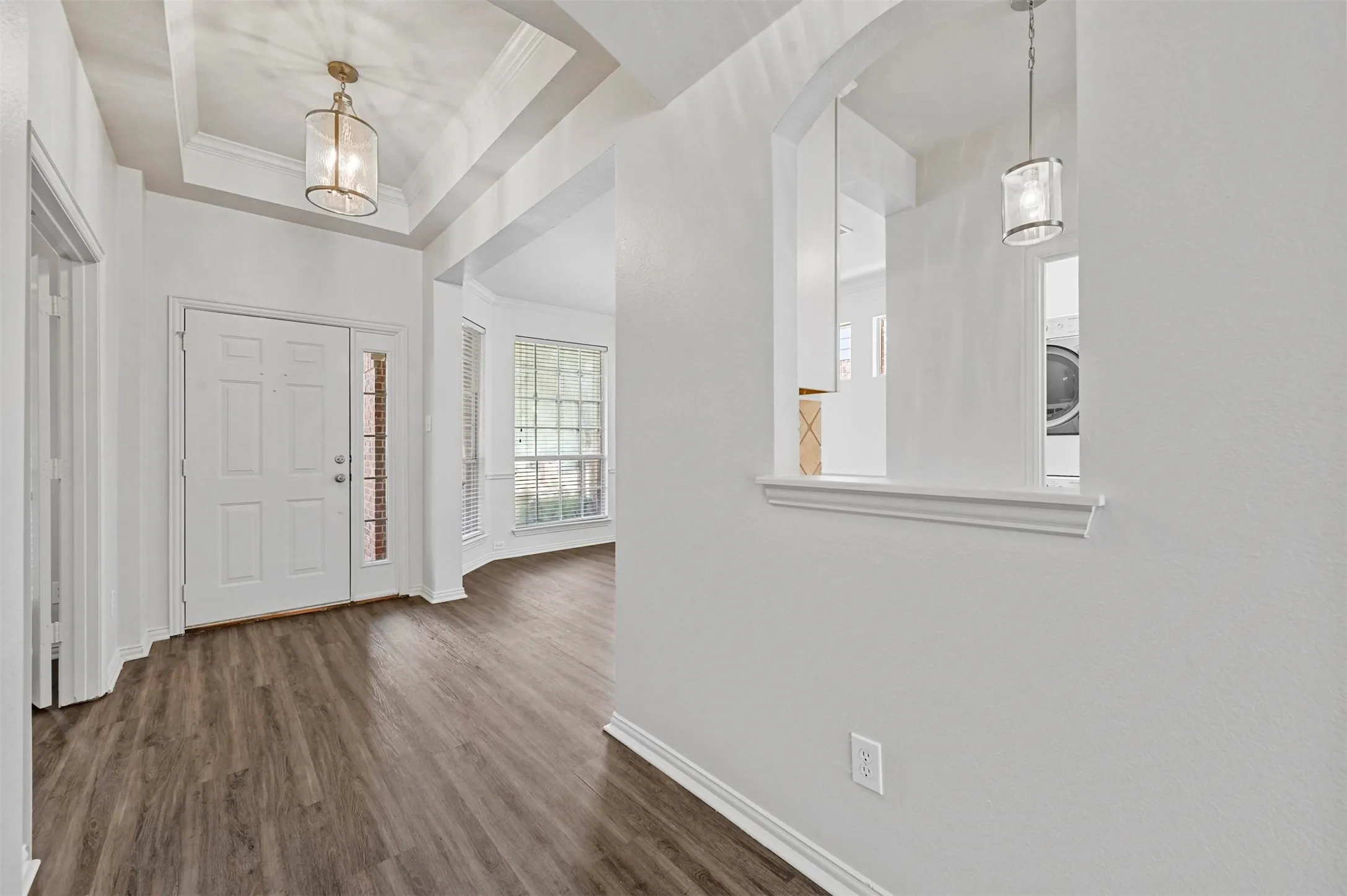 Welcoming foyer showcasing coffered ceiling detail, wood-finish flooring throughout, and abundant natural light from multiple windows