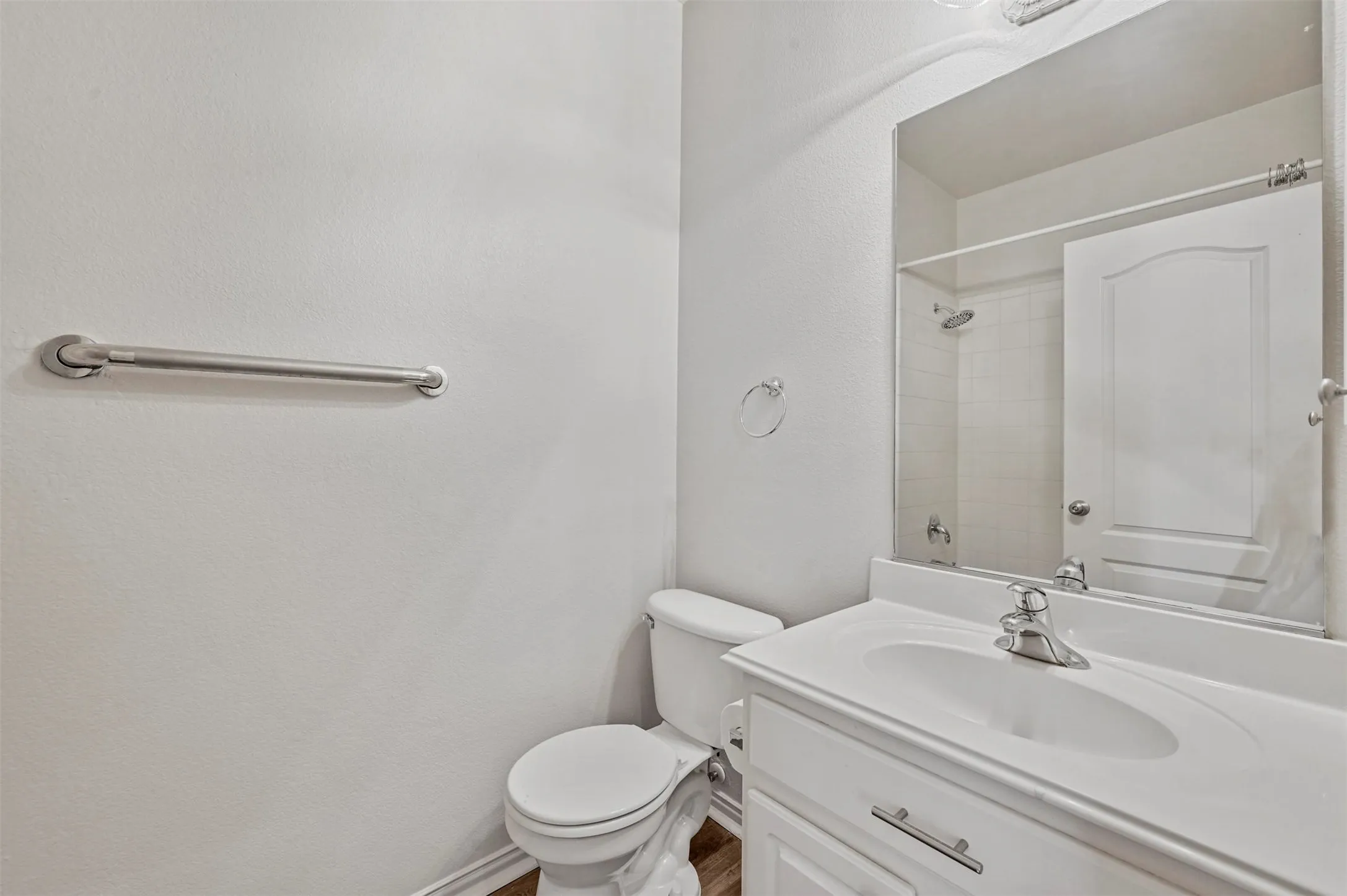 Bathroom featuring a single vanity with an integrated sink, polished chrome faucet, white cabinetry, and a framed mirror