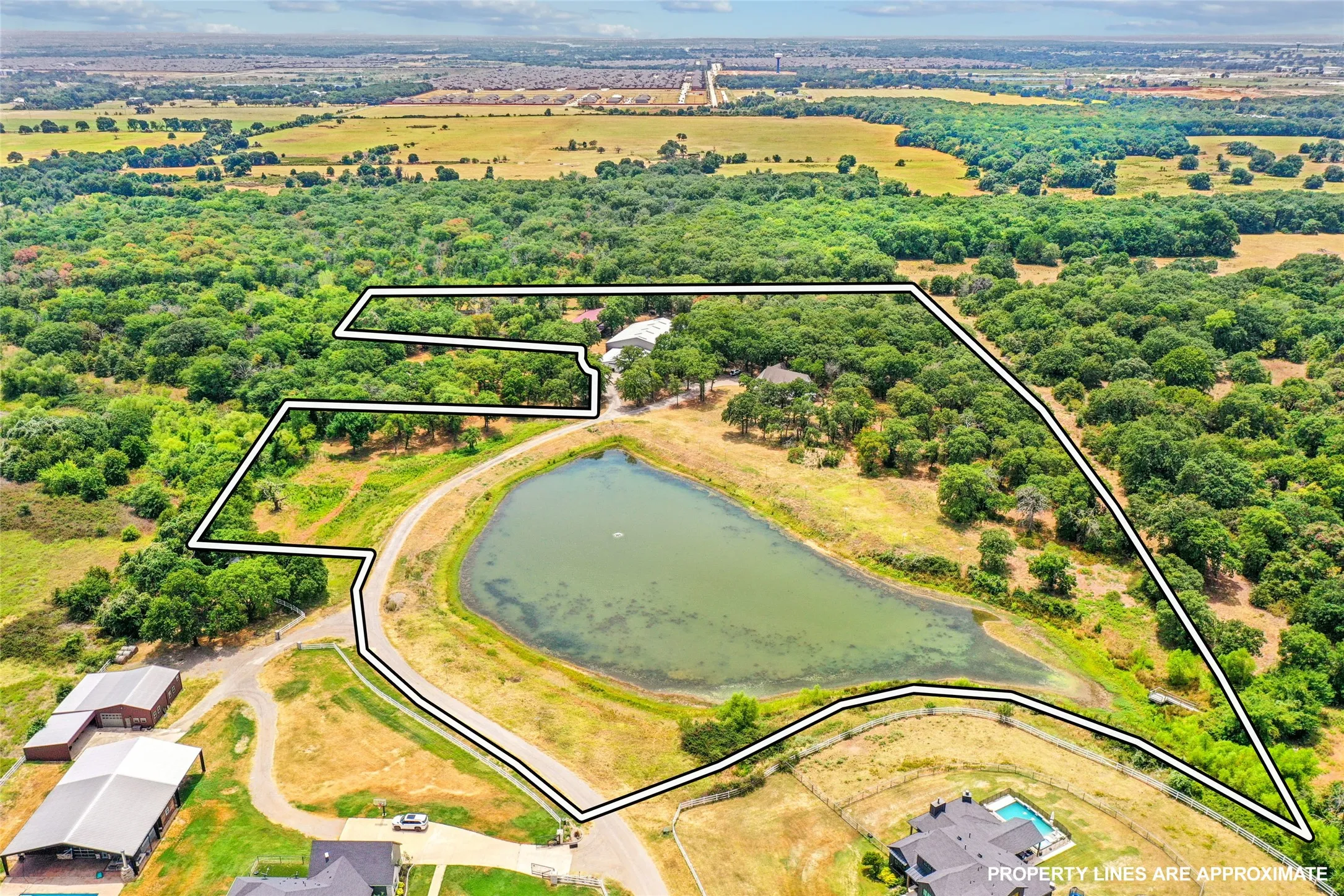 Expansive land parcel featuring a substantial pond, mature tree cover, and open grassy areas