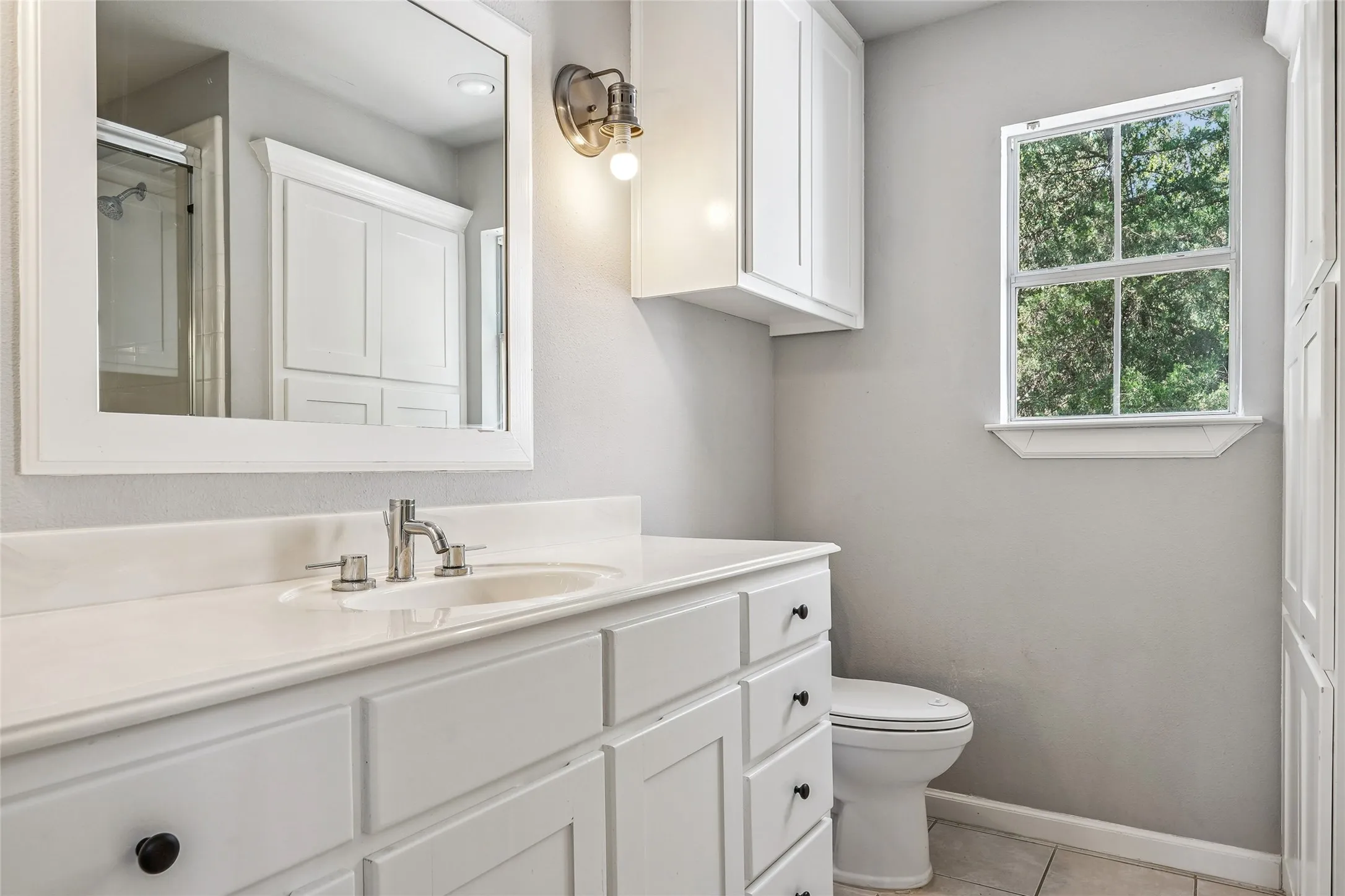 Bathroom featuring a white vanity with an undermount sink, brushed nickel faucet, and a large framed mirror
