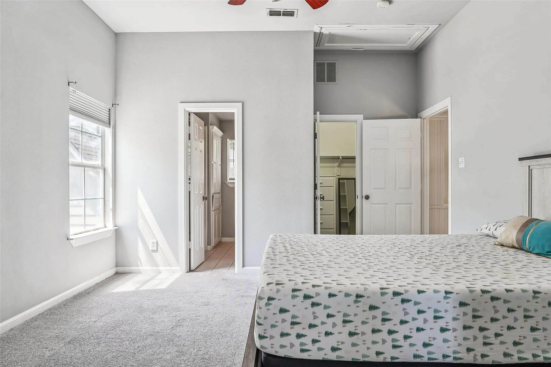 Spacious room featuring light gray wall paint, gray carpet flooring, and a ceiling fan
