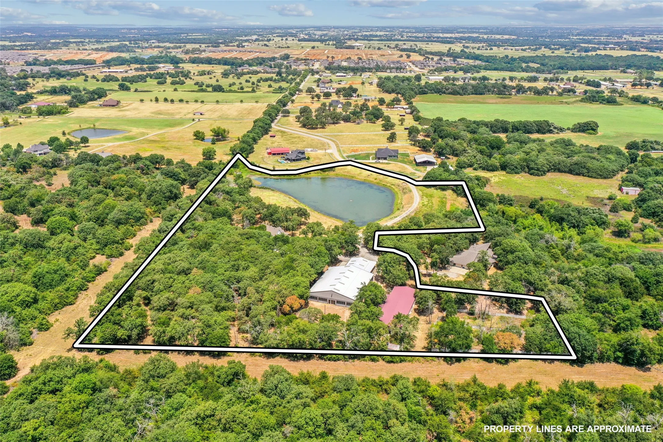 Expansive aerial view showcasing acreage with a private pond and surrounding mature trees