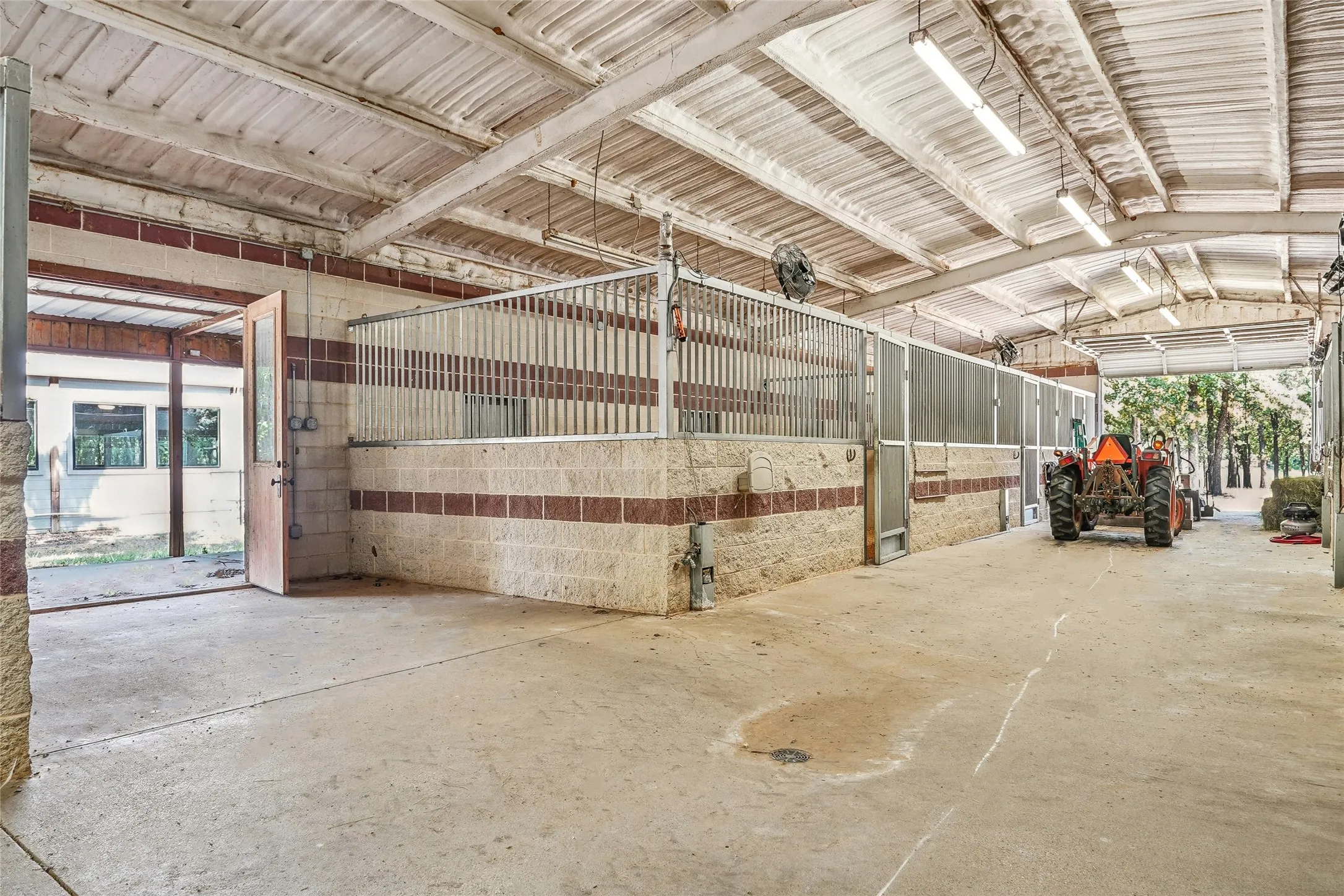 Spacious interior barn area featuring concrete flooring and a high corrugated metal ceiling with exposed beams