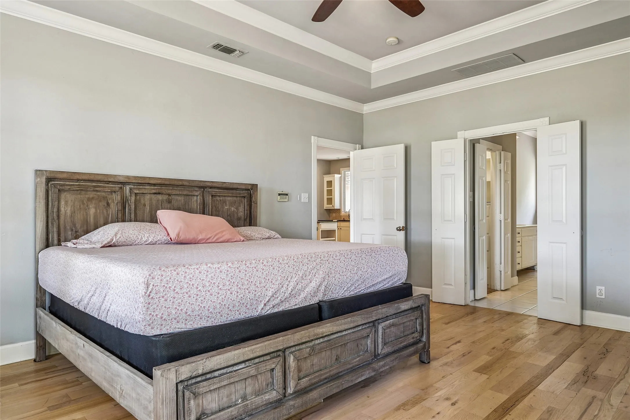 Spacious room featuring wood-finish flooring, a tray ceiling, and crown molding