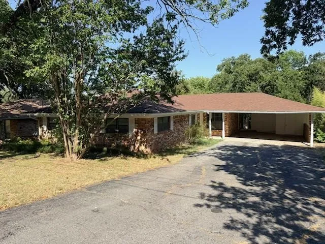 Brick exterior, attached carport, asphalt driveway, mature trees