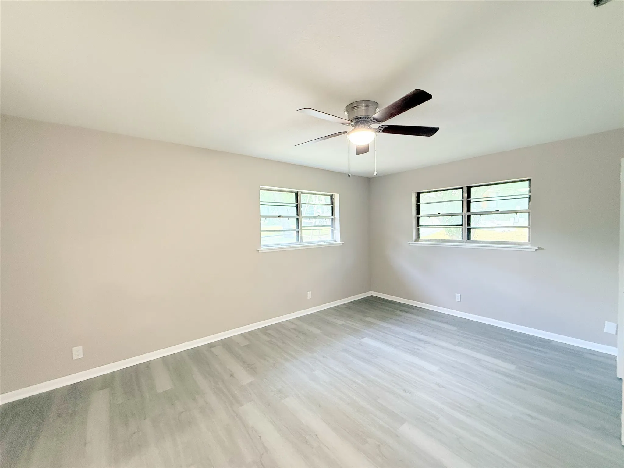 Spacious room featuring wood-finish flooring, light neutral wall paint, and white trim