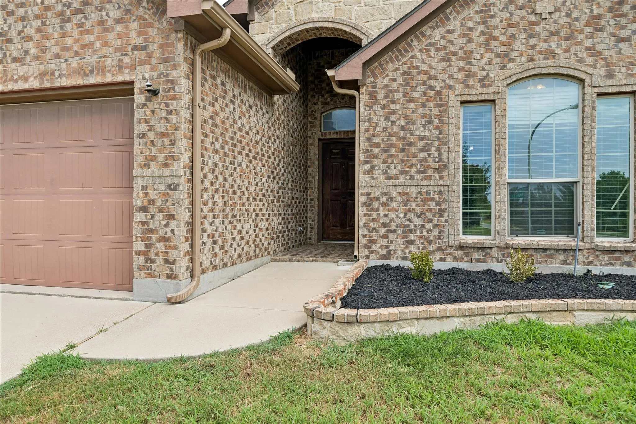 Brick exterior with a prominent arched entry, large arched window, and a built-in garage