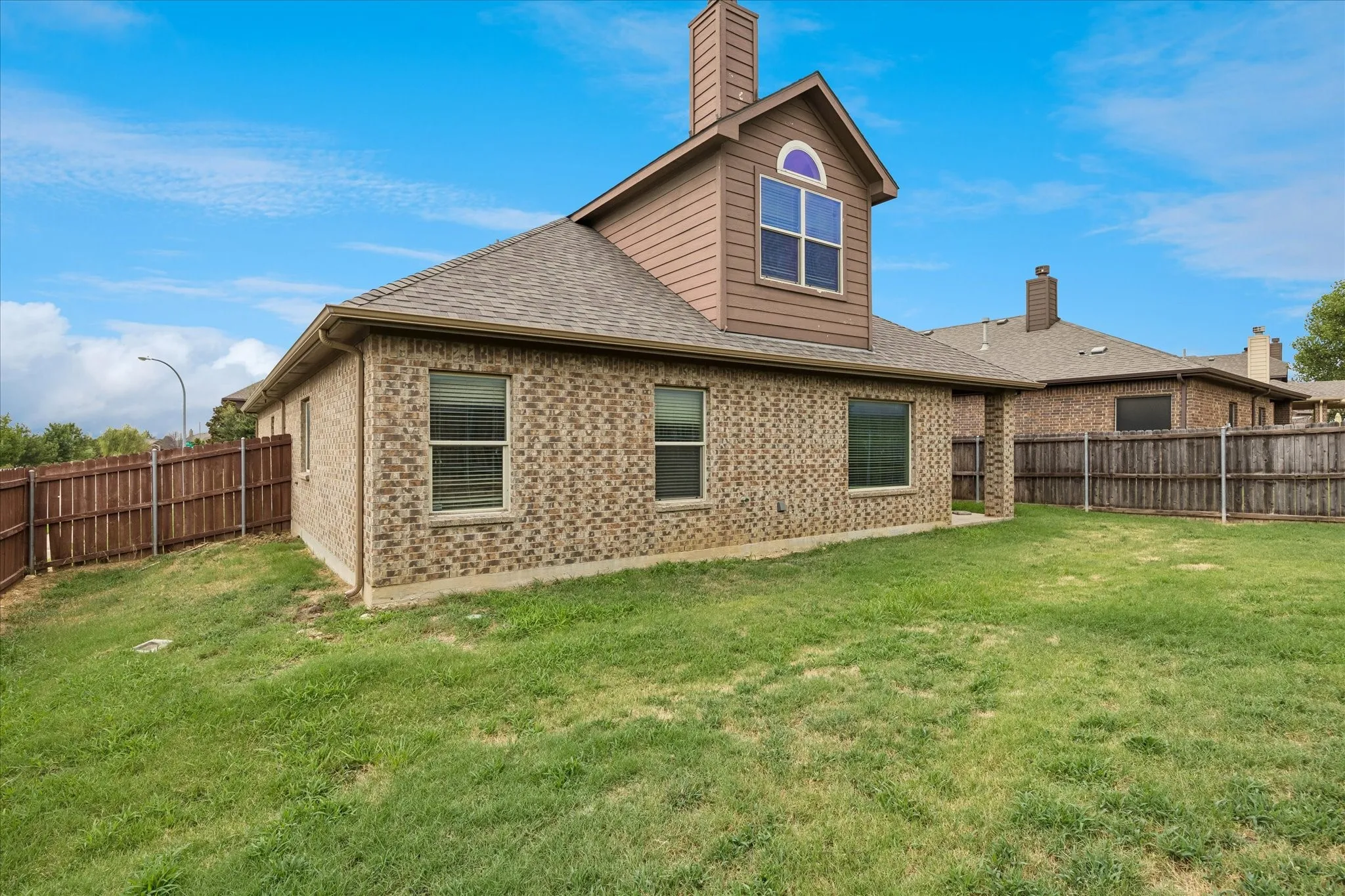 Exterior featuring brick veneer, shingle roof, and a privacy fence