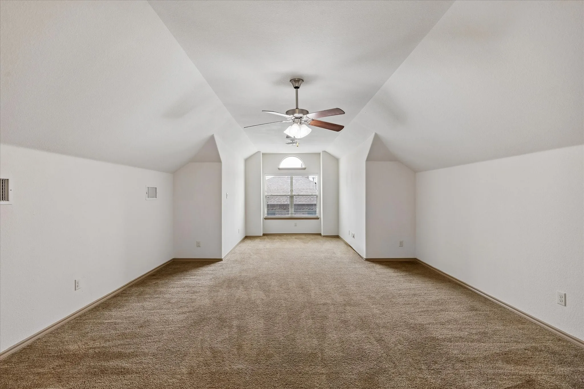 Carpeted room with a vaulted ceiling, ceiling fan, and arched window
