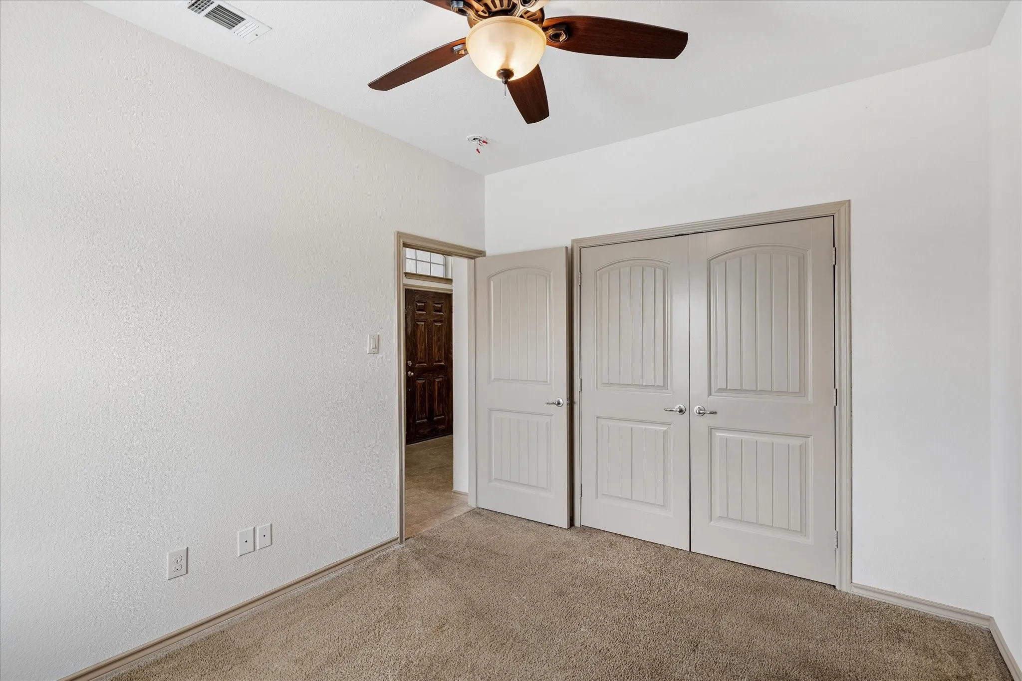 Carpeted room with a ceiling fan, white paneled doors, and light-colored walls