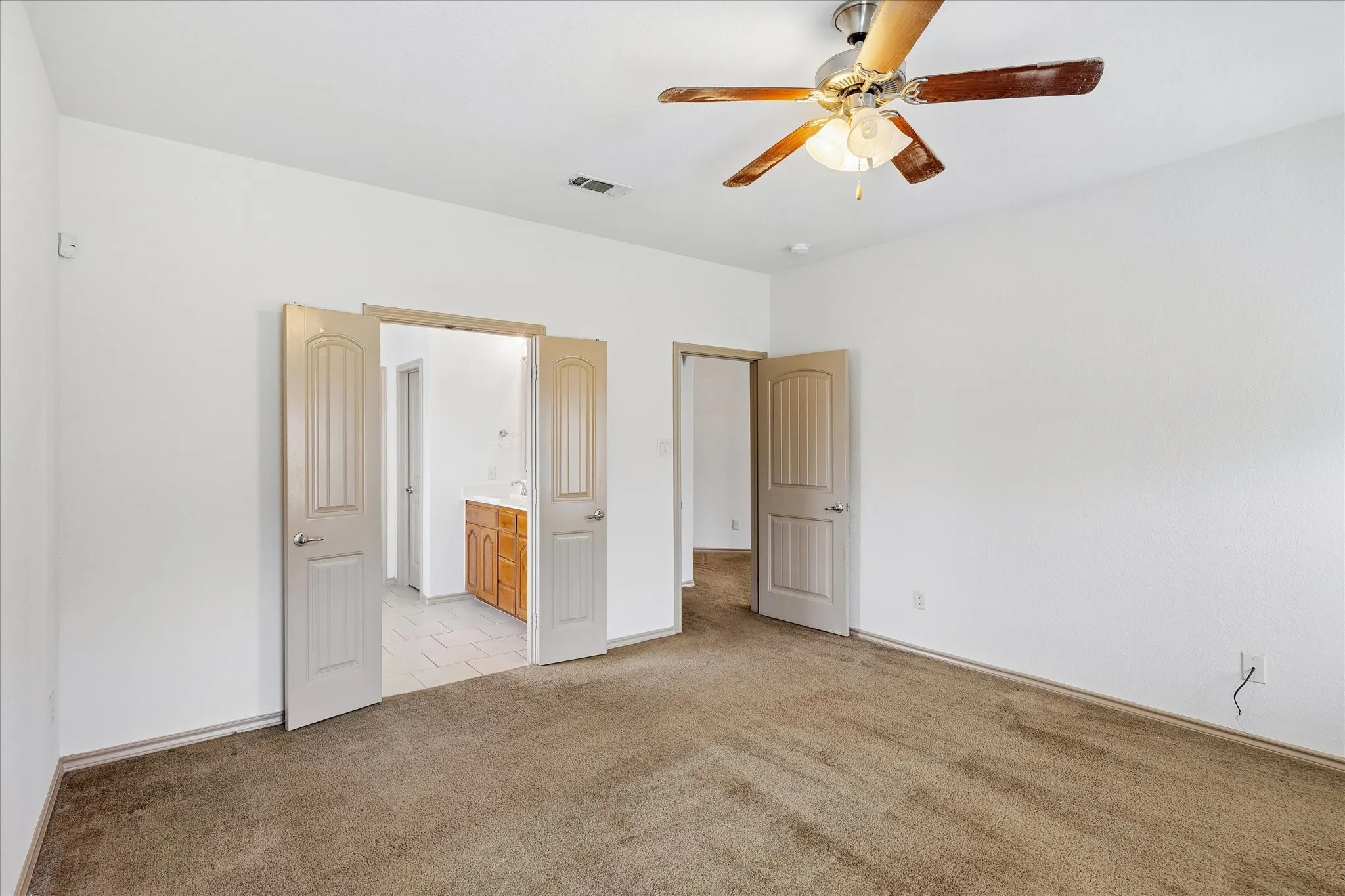 Spacious room with carpeted flooring, a ceiling fan, and white walls