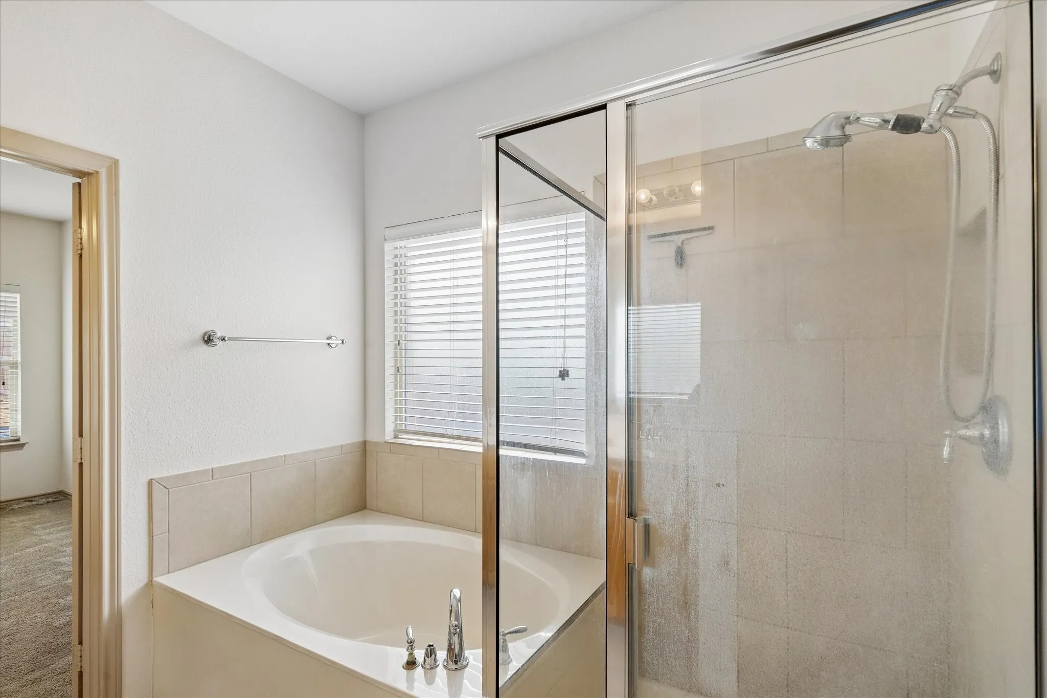 Garden tub and separate glass-enclosed shower with tile surround