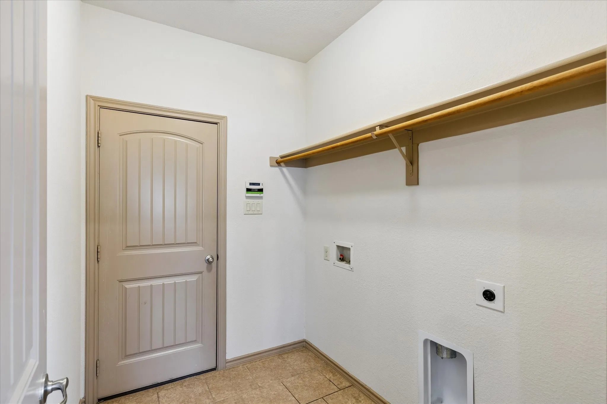 Laundry area featuring tile flooring, a built-in shelving unit, and plumbing hookups