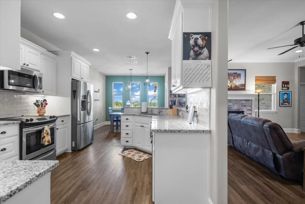 Open-concept kitchen with granite counters, breakfast nook, and view through to the living room's brick fireplace.