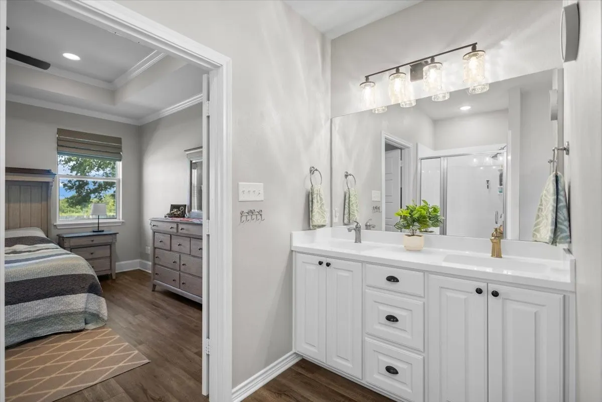 Dual-sink vanity with white countertop, framed mirror, and direct access to the primary bedroom.