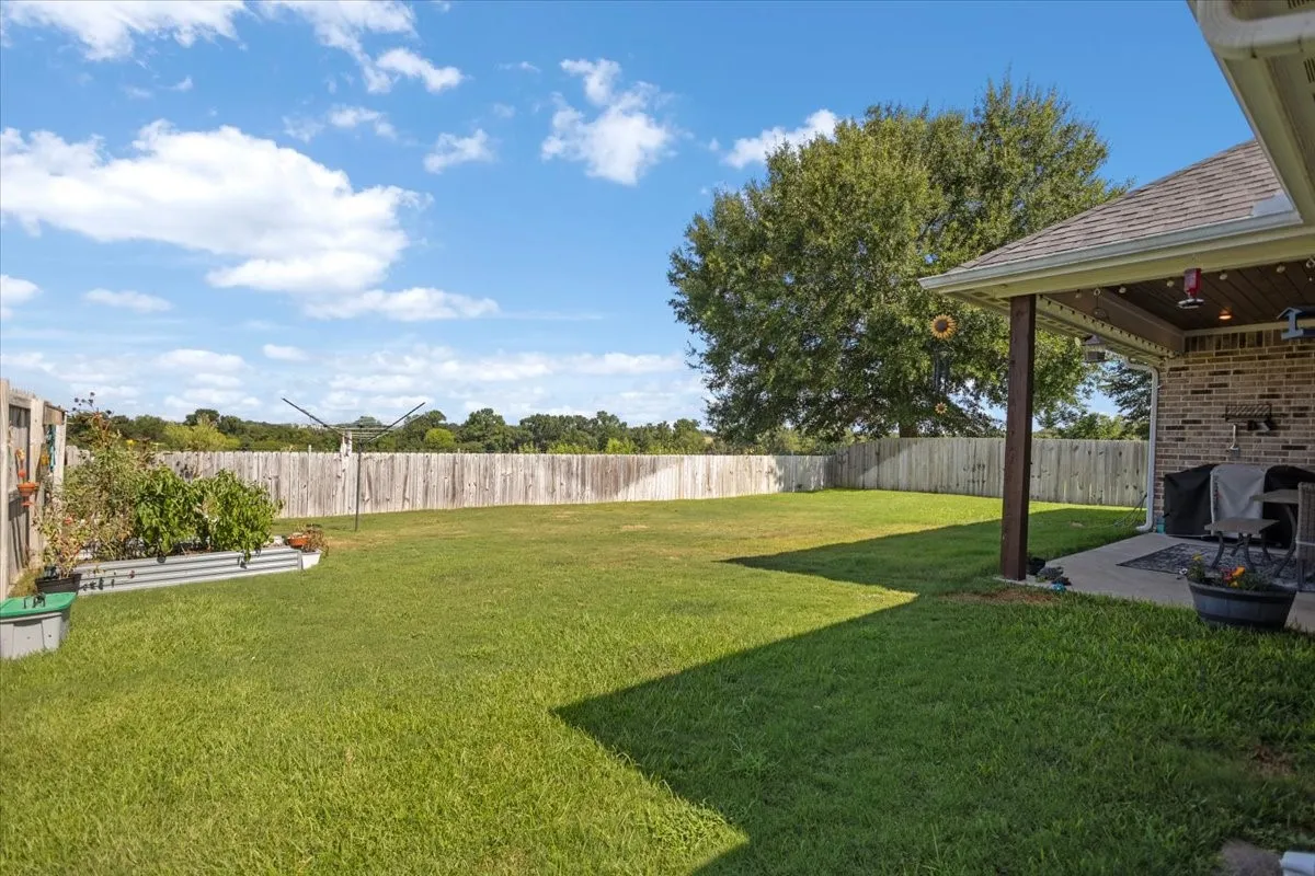 Fenced backyard with mature shade tree and covered patio off the rear of the home.