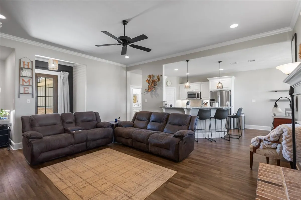 open flow into the kitchen, brick fireplace with mantel, and large windows on both sides bringing in natural light.