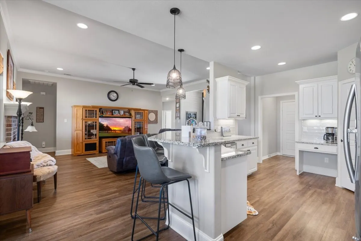 Open-concept kitchen with granite island seating, pendant lighting, and sightline into the living room