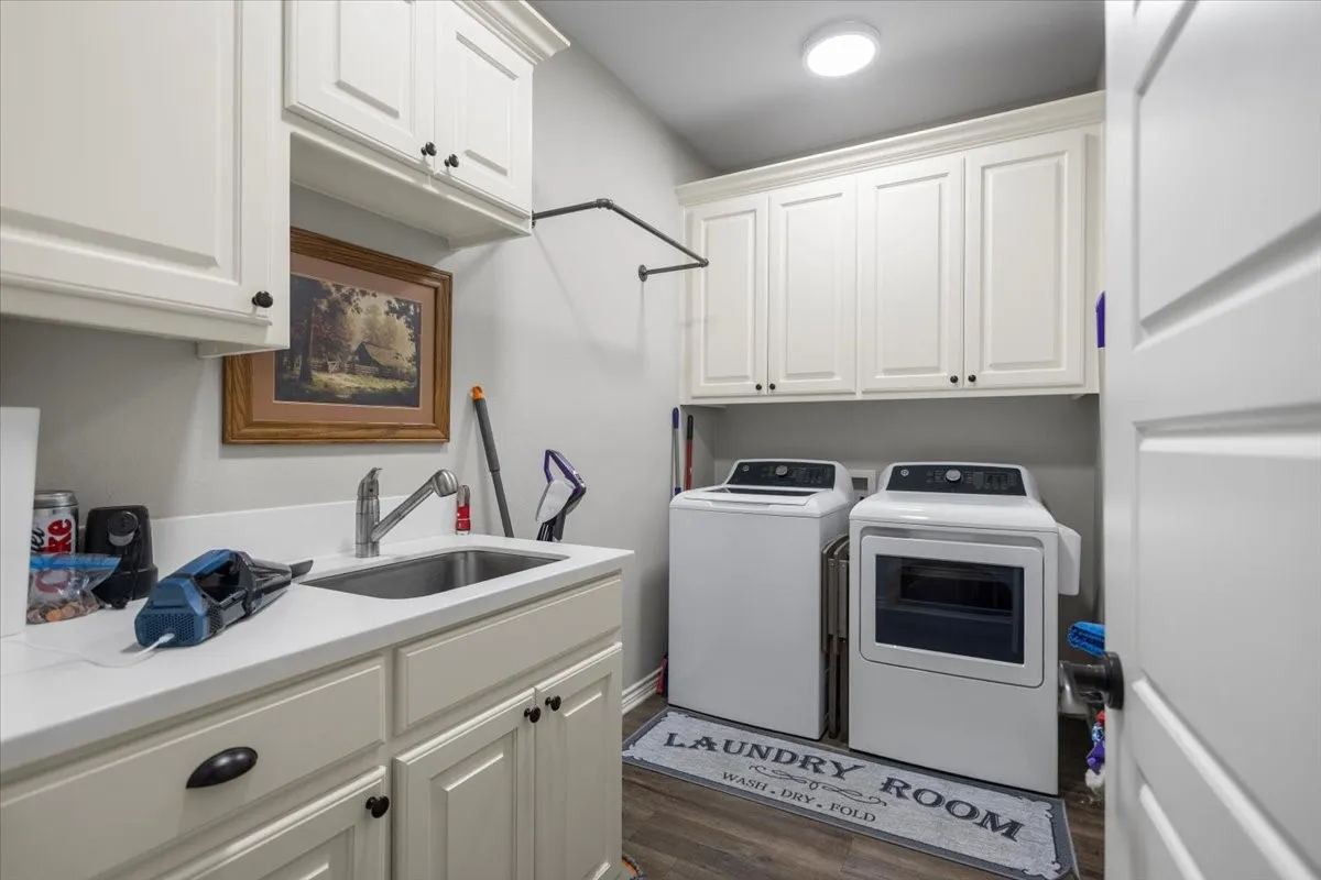 Second view of the laundry room showing hanging rod storage and additional cabinet space above the washer and dryer.