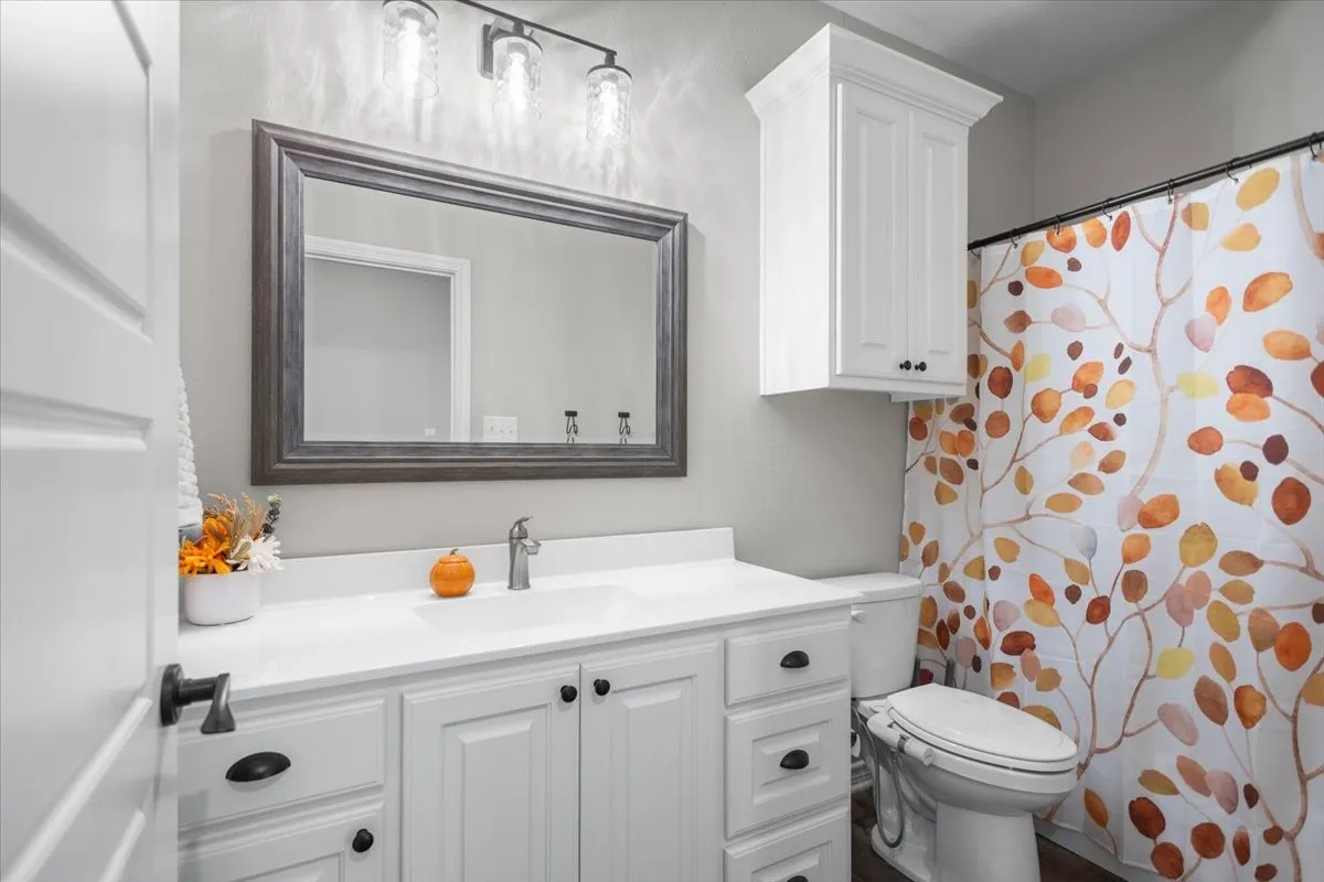Full bath with white vanity, framed mirror, and shower/tub combo