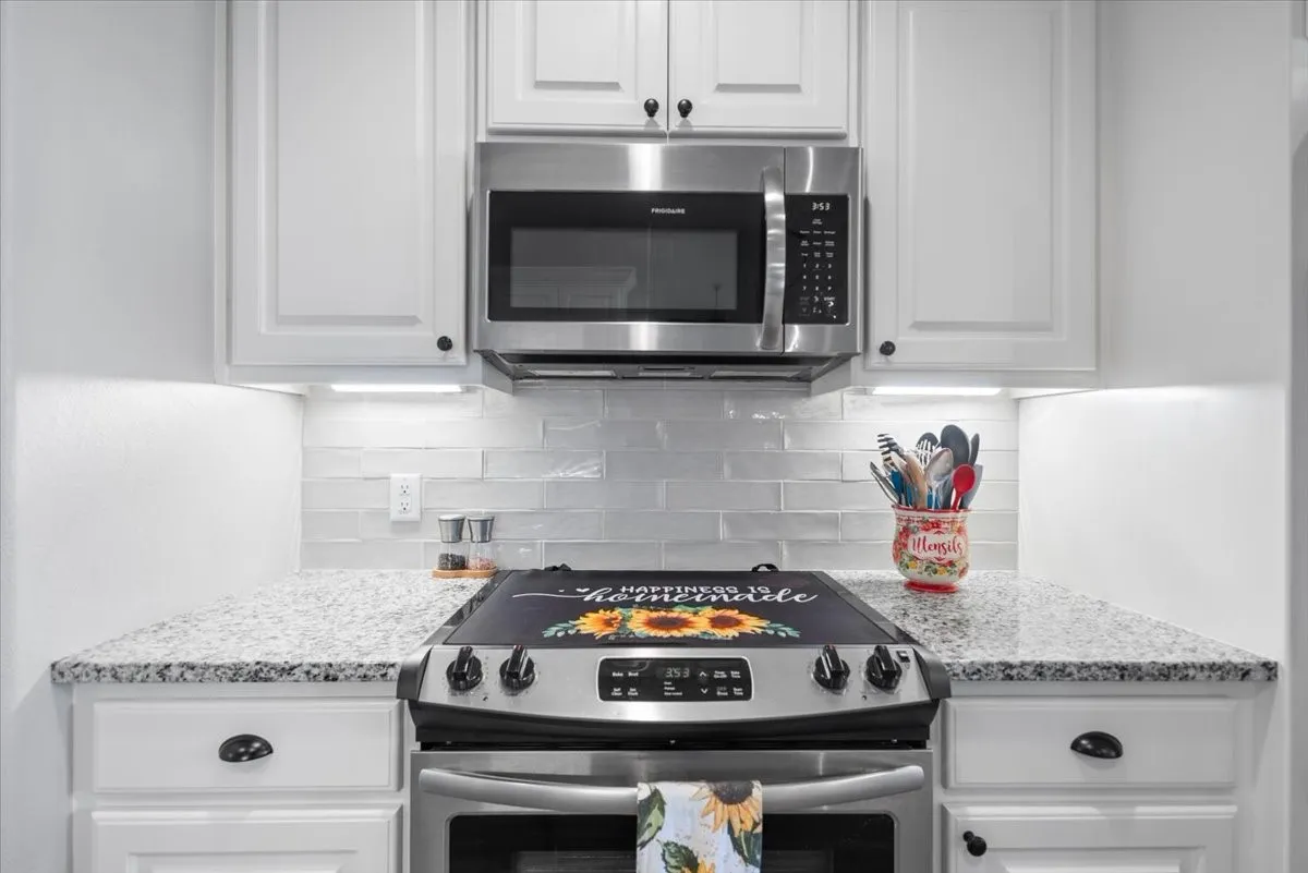 Stainless range and microwave with white subway tile backsplash and granite countertops.