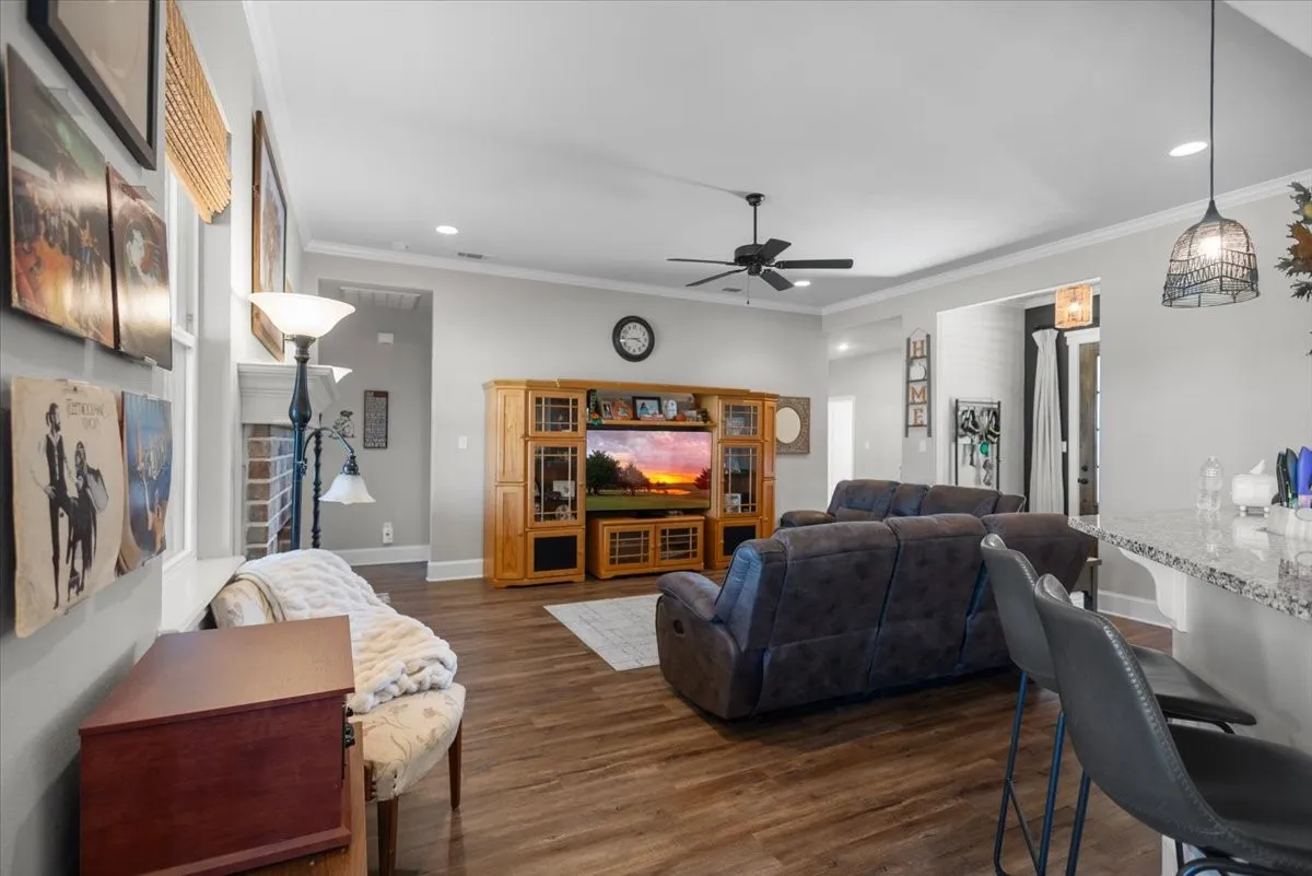 Open living area with wood-look flooring, Ceiling fan and recessed lighting and brick fireplace