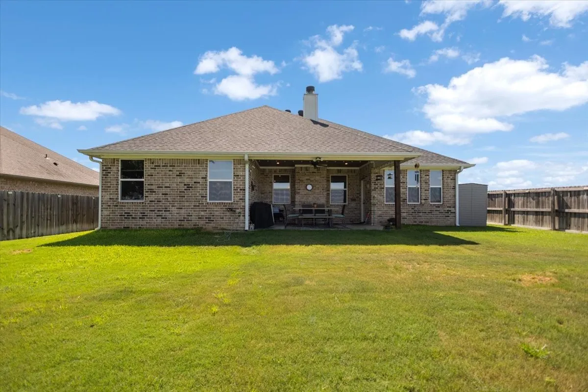 Additional rear view showing brick construction, storage shed, and full fenced yard.