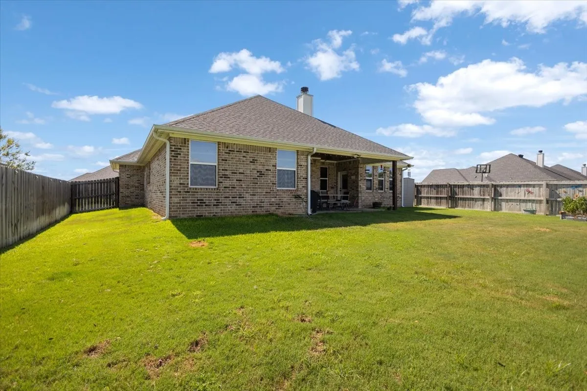 Additional rear view showing brick construction, storage shed, and full fenced yard.