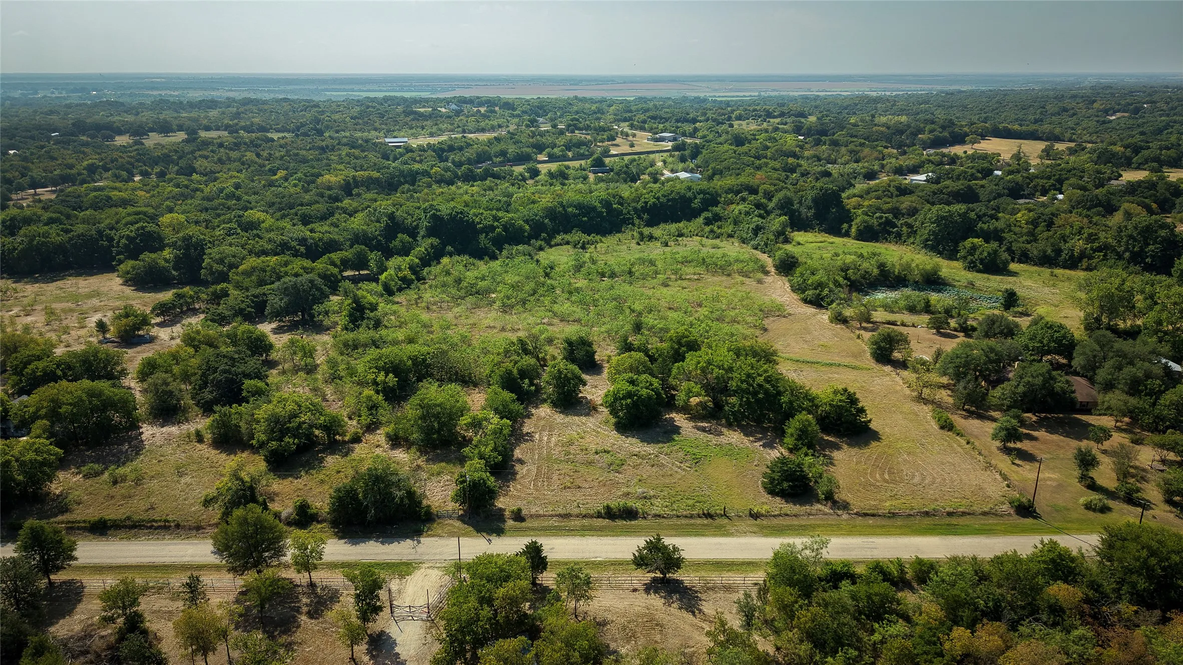 Expansive acreage featuring a mix of open fields and mature tree cover
