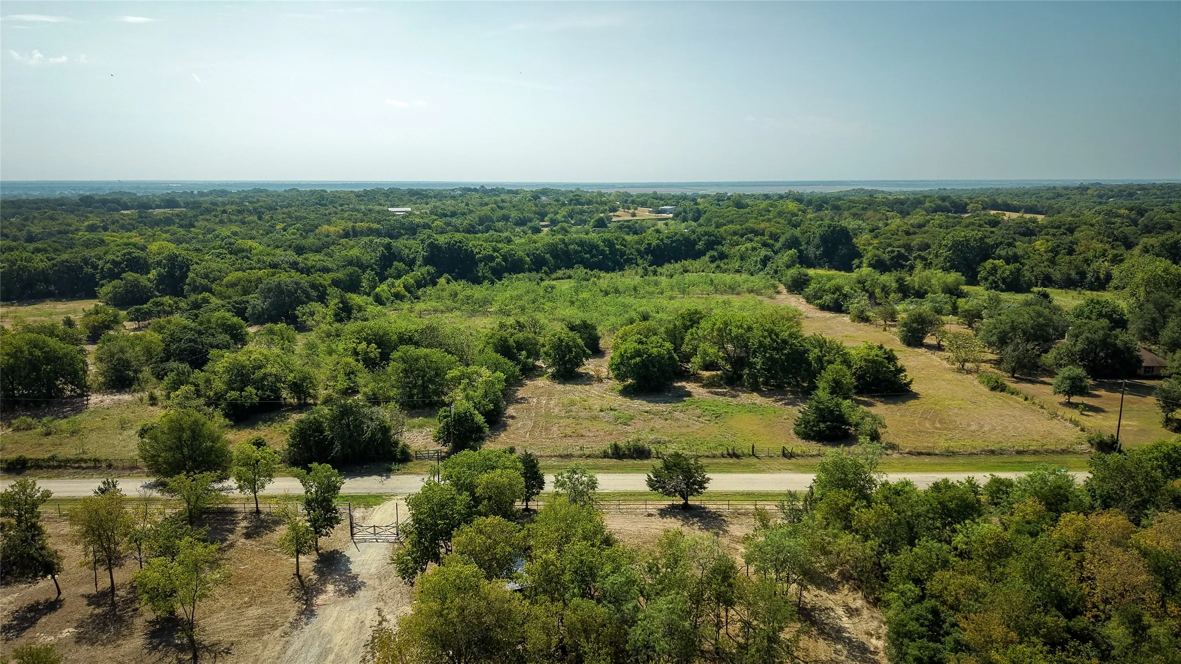 Expansive treed landscape featuring a natural terrain, open clearings, and a partially paved road