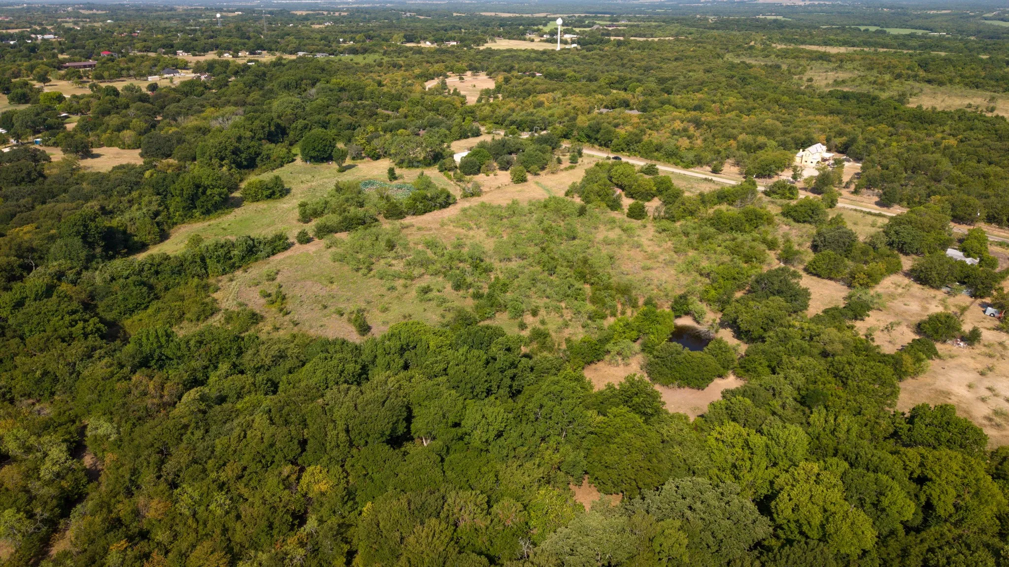 Expansive acreage featuring diverse tree coverage, open clearings, and a residential structure