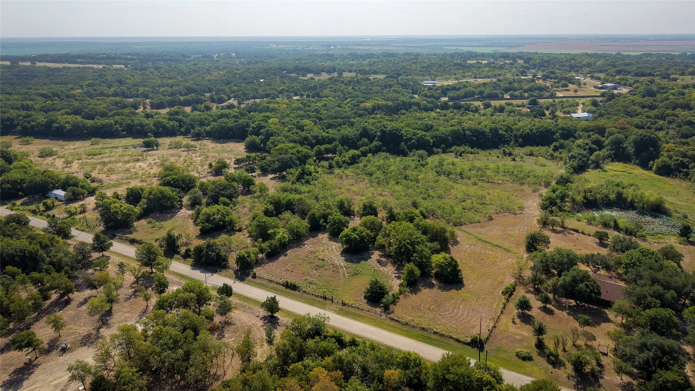 Expansive land parcel featuring open fields and mature tree coverage