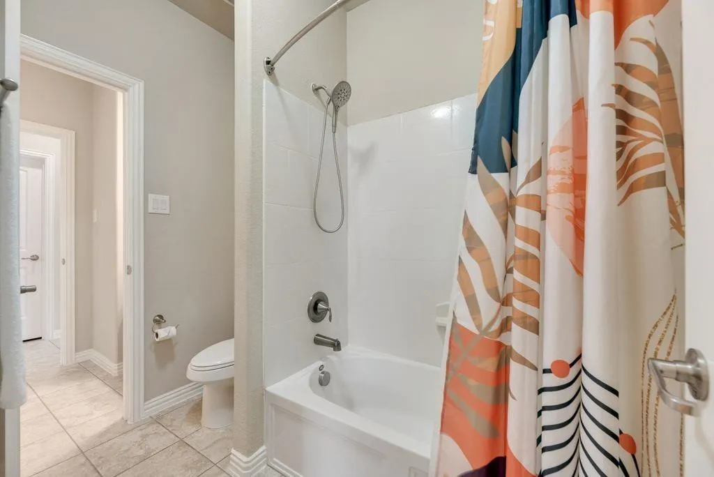 Bathroom featuring shower / bathtub combination with curtain and toilet