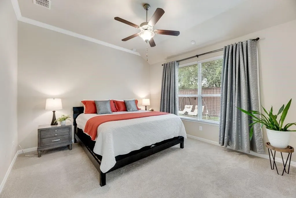 Bedroom featuring light carpet, crown molding, ceiling fan, and lofted ceiling