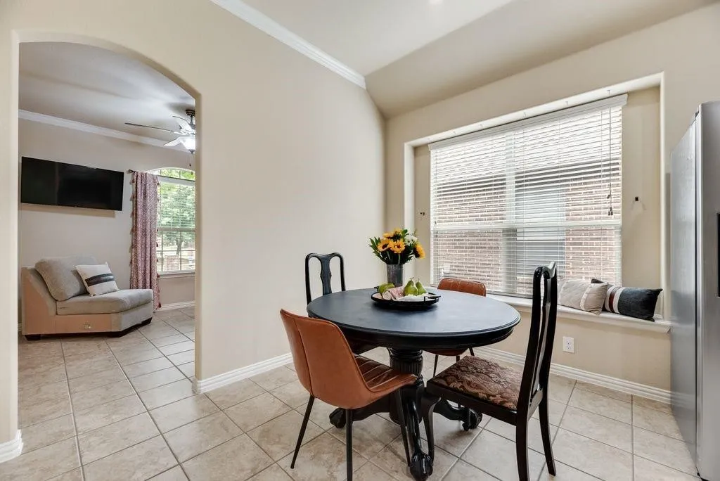 Dining room featuring ornamental molding, a ceiling fan, light tile patterned floors, and vaulted ceiling