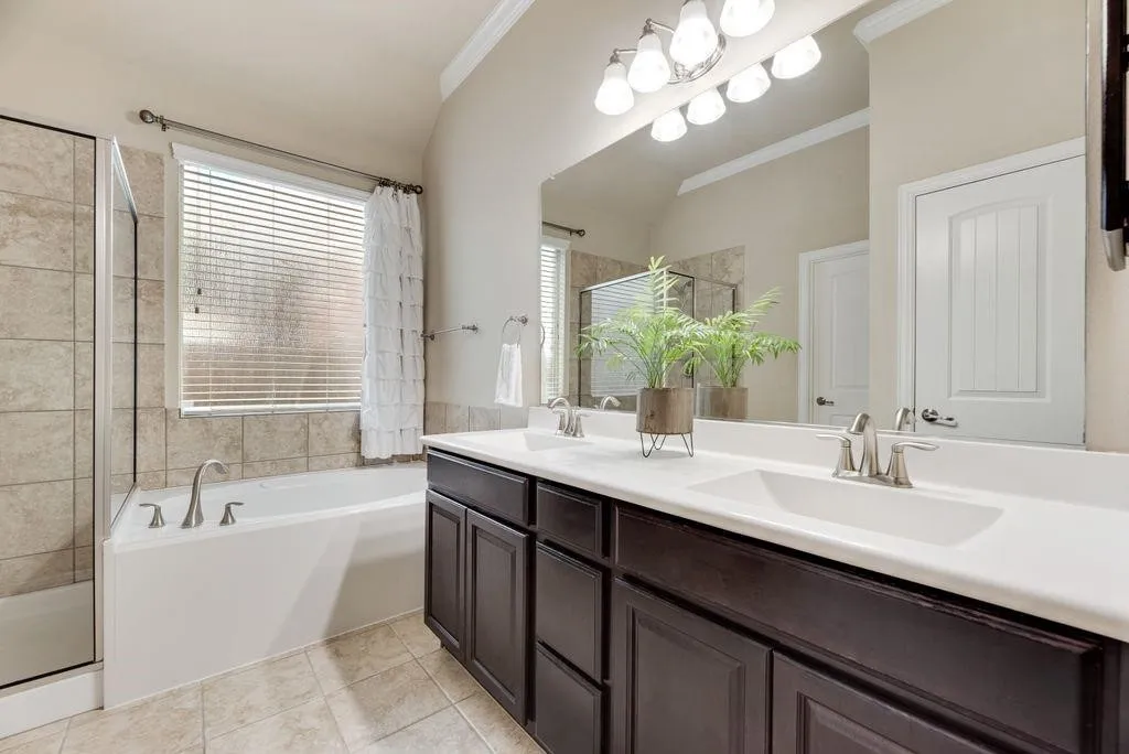 Full bathroom with lofted ceiling, double vanity, crown molding, a bath, and tile patterned floors
