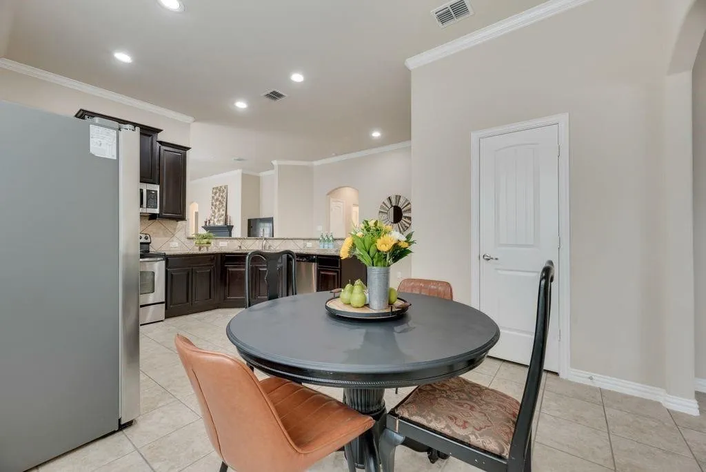 Dining area with arched walkways, ornamental molding, light tile patterned floors, and recessed lighting