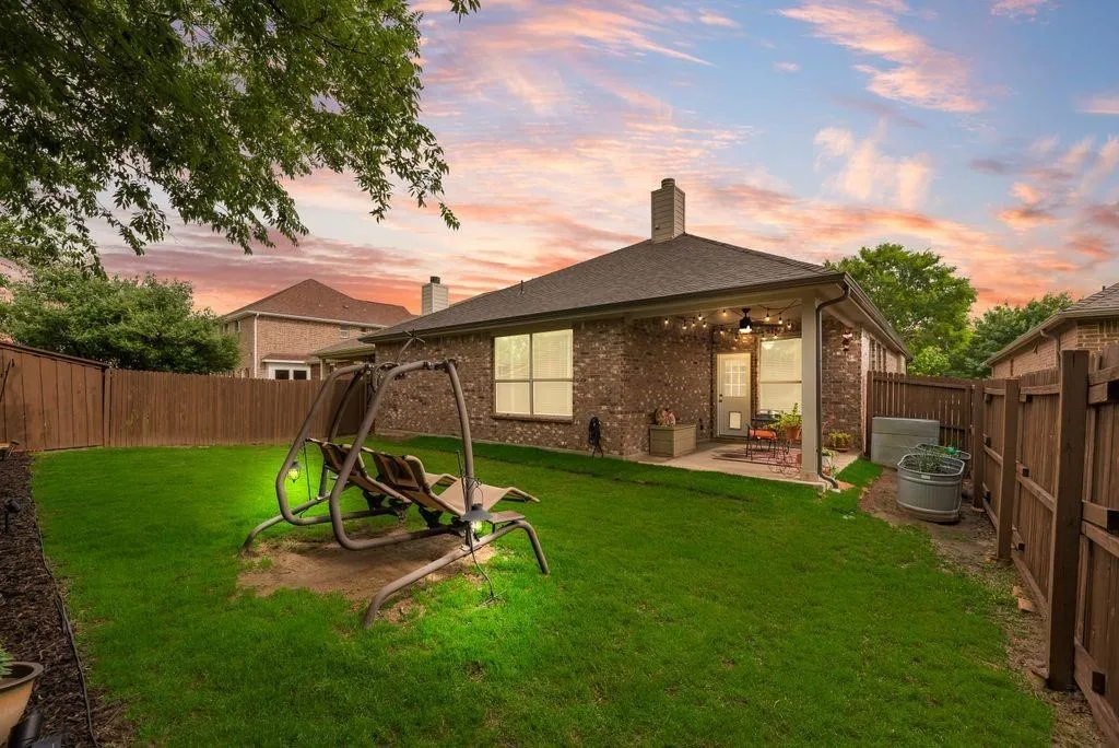 Rear view of property with a fenced backyard, a patio area, brick siding, a chimney, and a shingled roof