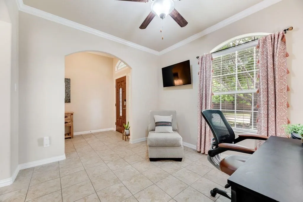 Home office featuring arched walkways, a ceiling fan, ornamental molding, and light tile patterned flooring