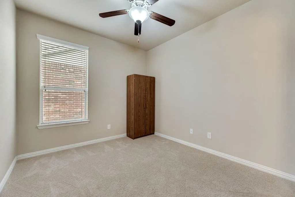 Empty room featuring light carpet and a ceiling fan