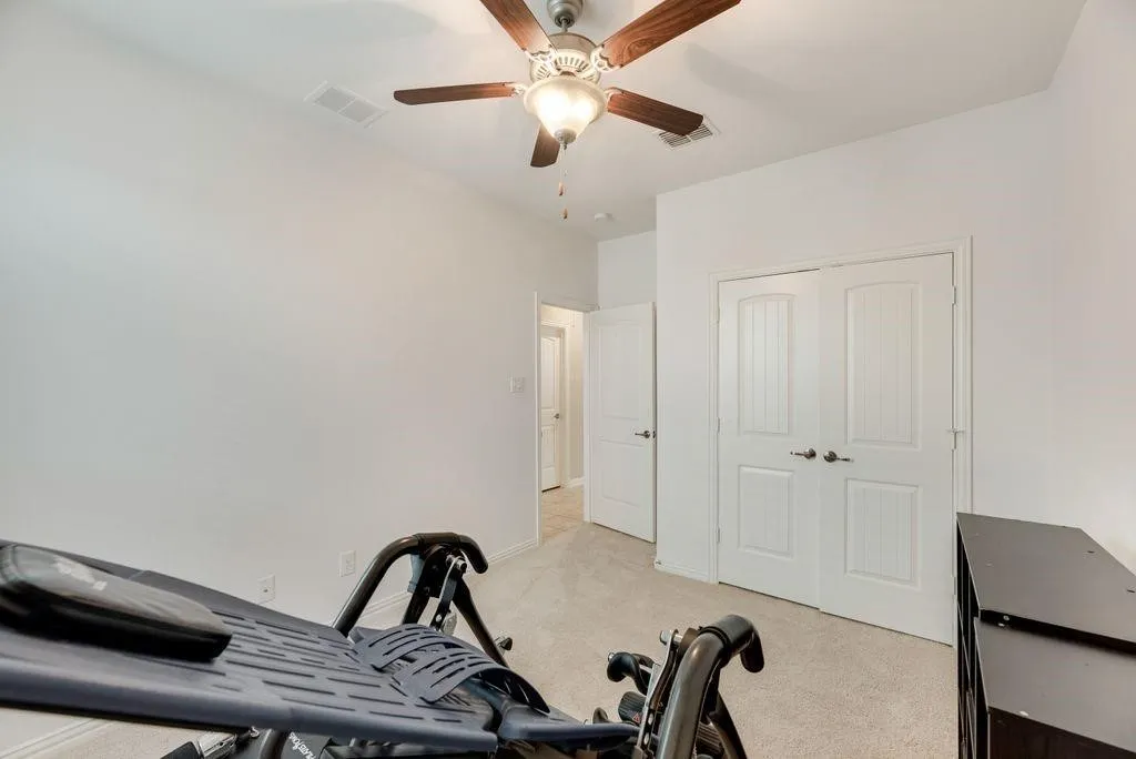 Exercise room featuring light colored carpet and ceiling fan