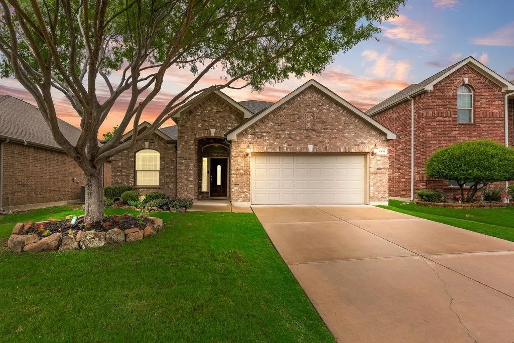 Traditional home featuring a garage, concrete driveway, a front yard, and brick siding