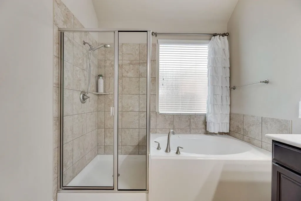 Bathroom featuring a bath, a shower stall, and vanity