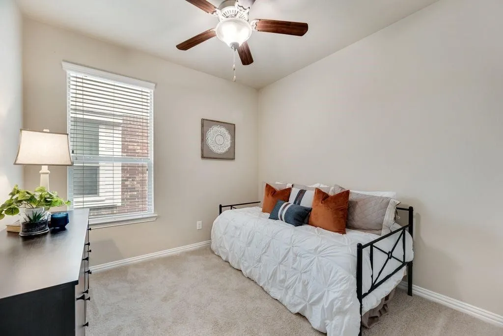 Bedroom with light colored carpet, multiple windows, and ceiling fan