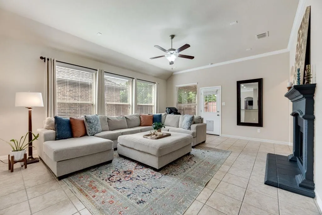 Living area with light tile patterned floors, ceiling fan, and crown molding