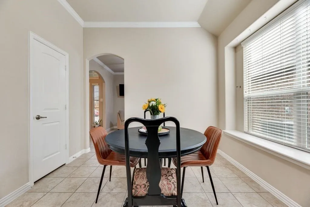 Dining space featuring arched walkways, light tile patterned flooring, and ornamental molding