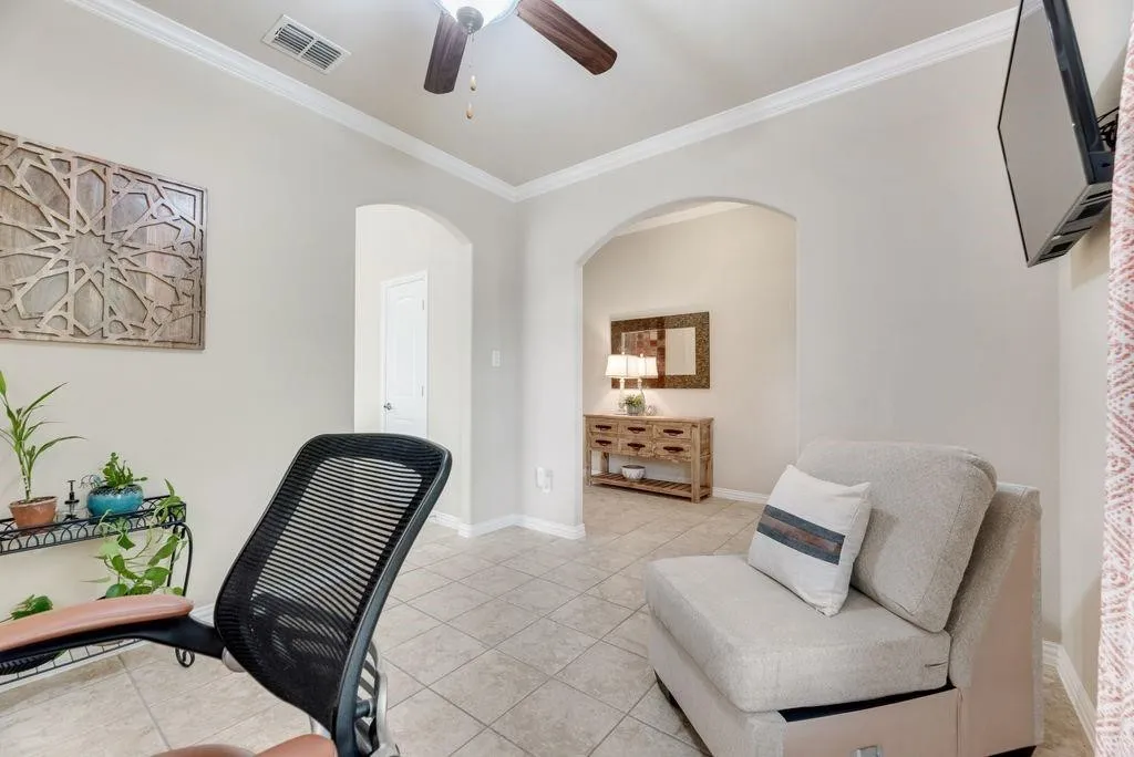 Home office with arched walkways, light tile patterned flooring, crown molding, and ceiling fan