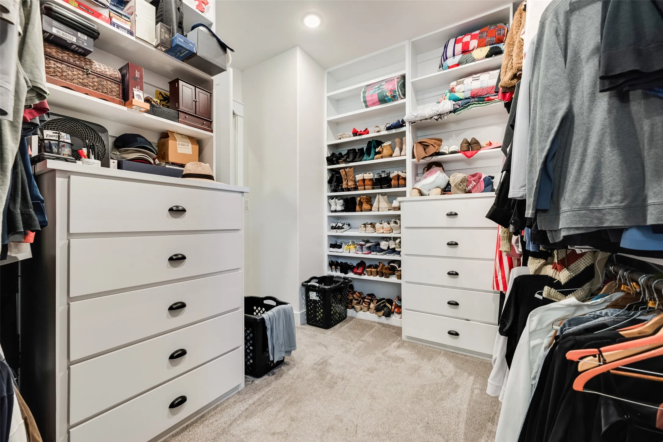 Custom closet system featuring built-in white cabinetry, integrated shelving, hanging rods, and multiple drawer units