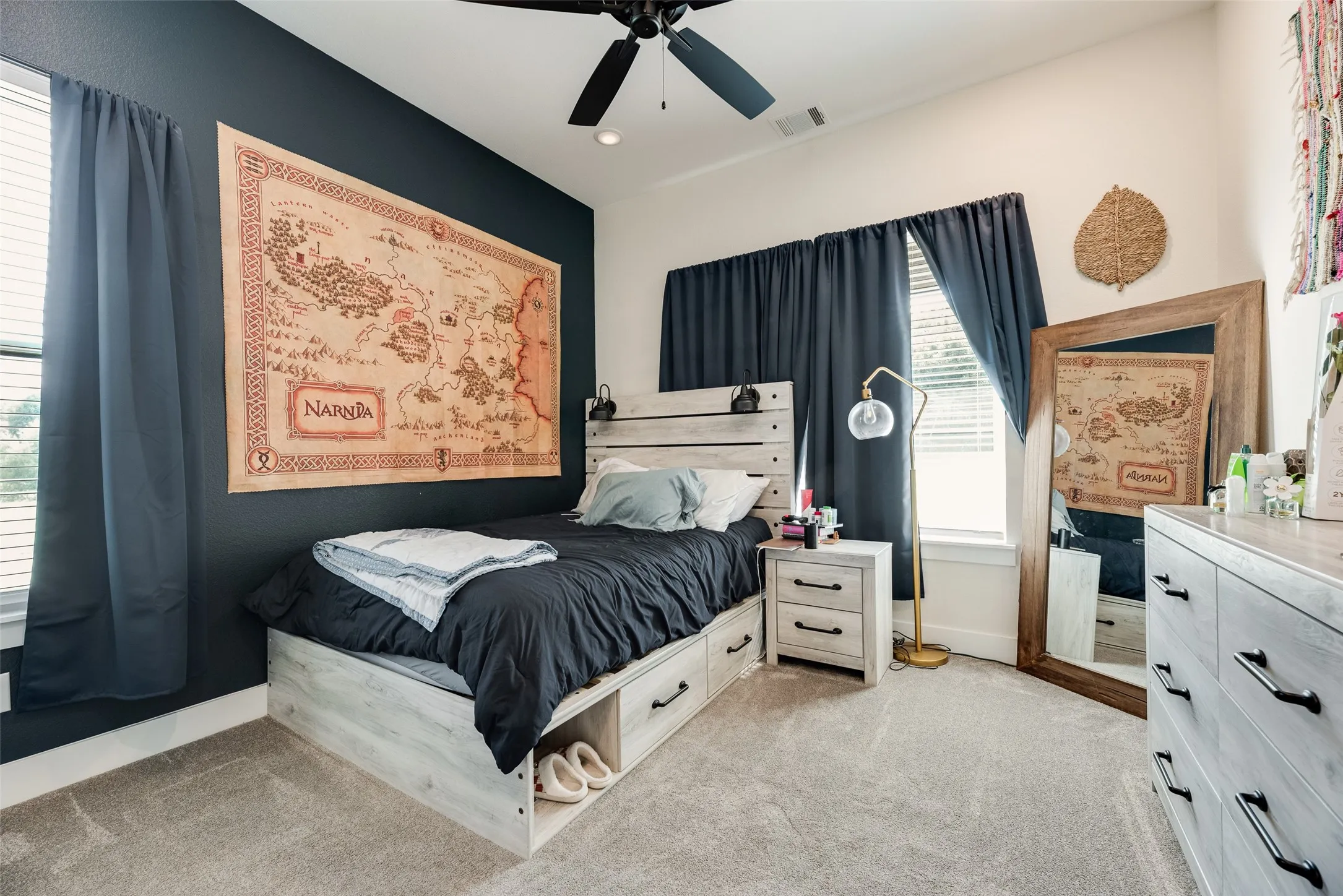 Carpeted bedroom featuring a dark accent wall, light-colored walls, and a ceiling fan with integrated lighting